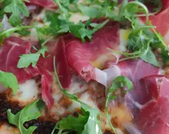 Step <p>Horneamos colocando la bandeja durante 7 minutos (250°C) lo más arriba posible y 7 minutos lo más abajo posible en el horno. Retiramos del horno y colocamos la rucula y el jamón. Regamos con aceite de oliva.</p><p>Buen provecho</p> illustration