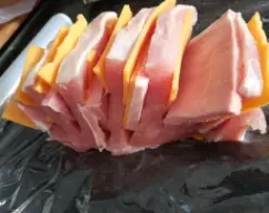 Step <p>Cortamos la loncha de jamon york que se ajuste a los trozos de lomo. Introduzcimos entre cada filete un trozo de jamón york y una de queso. Espolvoreamos con la sal y la pimienta. Envolvemos con film transparente bien ajustado pinchamos con el tenedor y lo volvemos a envolver. Tiene que estar apretado y sin aire, coloquelo en el cestillo.</p> illustration